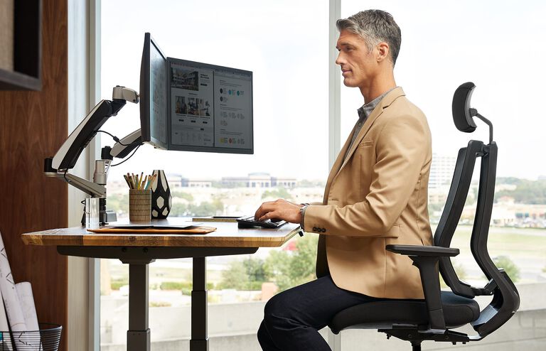 Professional working in office and sitting on an office chair using a variety of Vari products