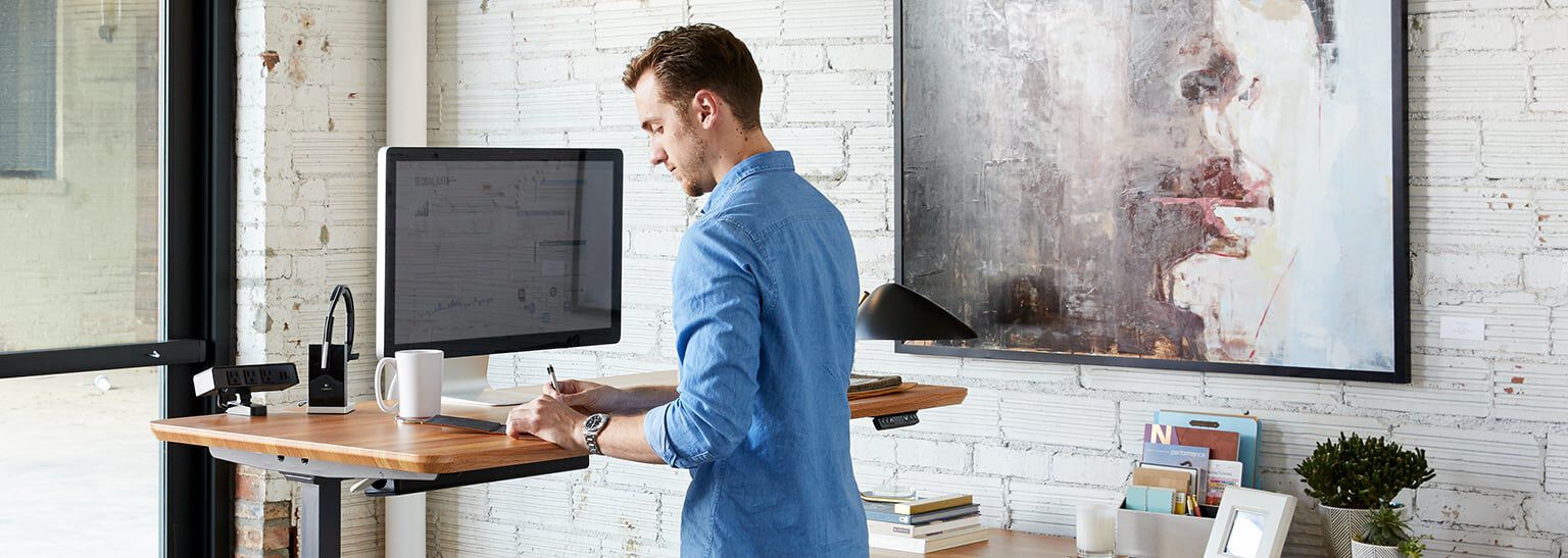 professional working at electric standing desk in a home office