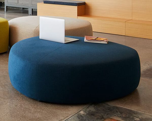 large ottoman with laptop and notebook on top in lounge setting