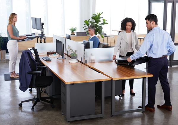 varidesk standing desk converter being set in place atop a fixed height desk