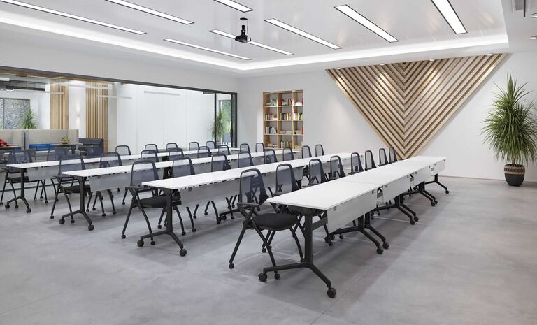 A large room filled with white rolling tables and chairs that can be moved and stored to repurpose the space.