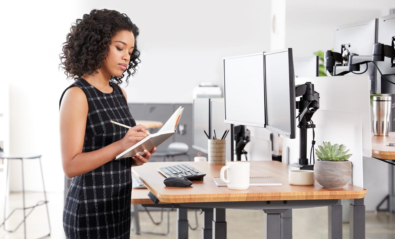 Professional writing in notebook at electric standing desk