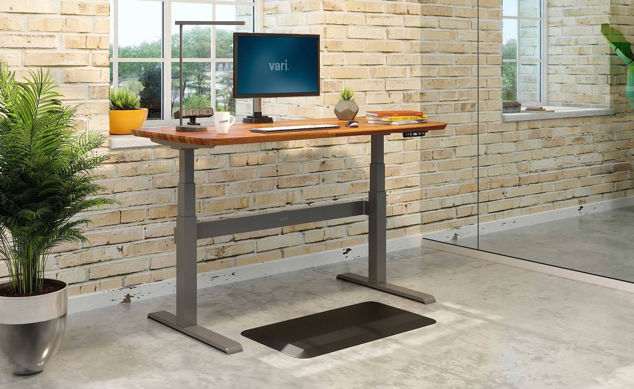 Vari Electric Standing Desk in butcher block with accessories in home office.