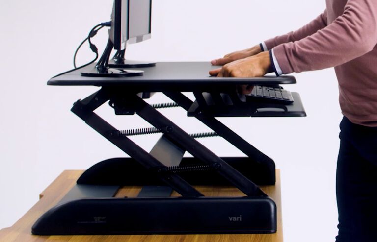 Individuals adjusting VariDesk Cube Plus 40 to seated position