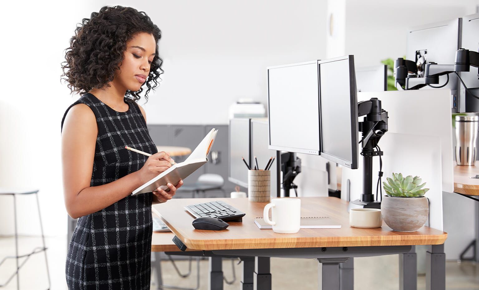 Professional writing in notebook at electric standing desk