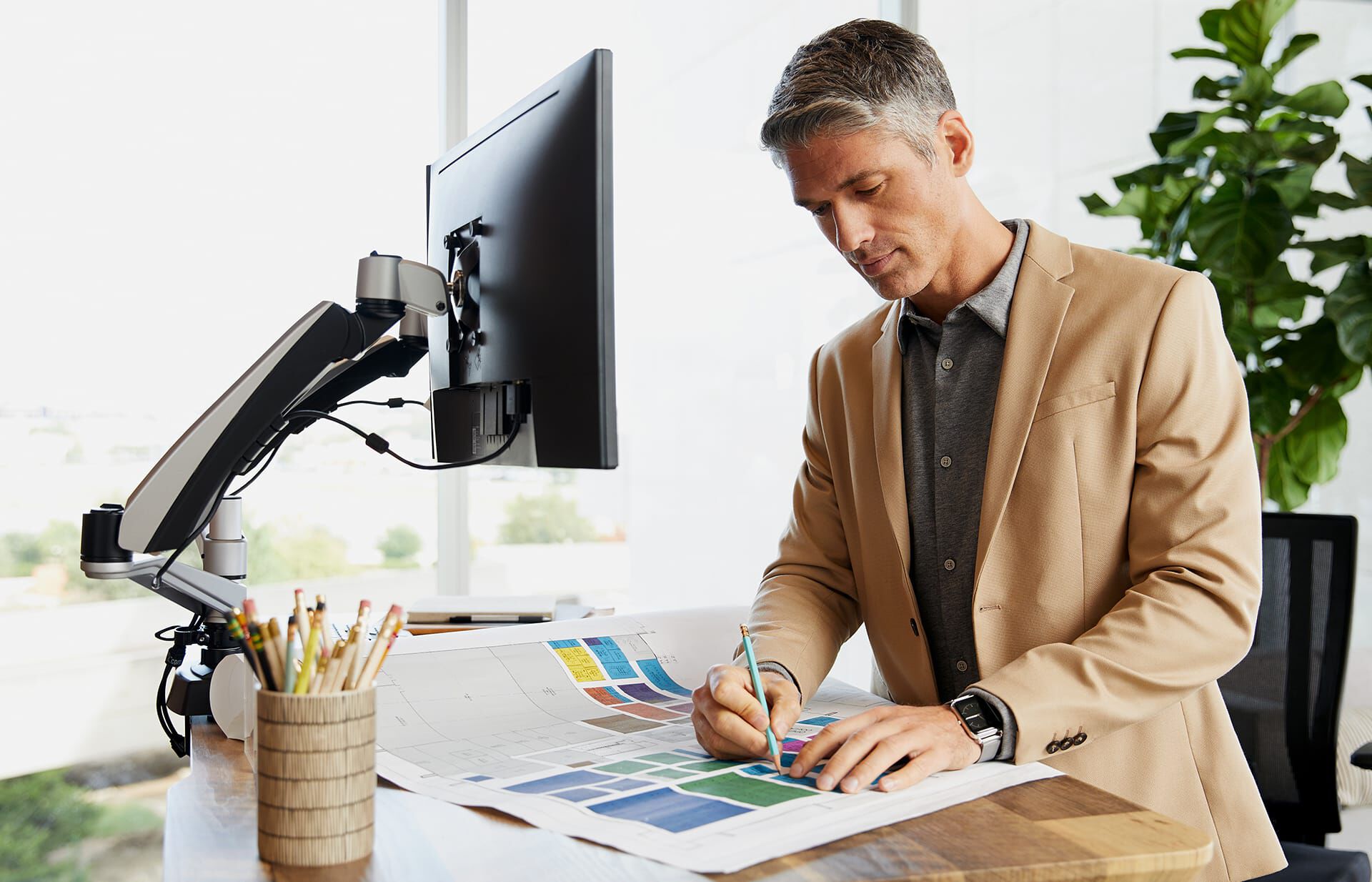 Individual working at Electric Standing Desk 60x30 with monitor arms attached