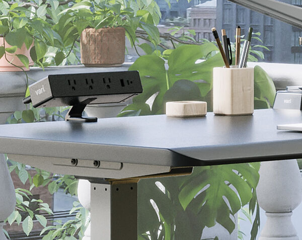 Individual is assembling the Electric Standing Desk 60x30 by locking the legs of the desk into place with one hand