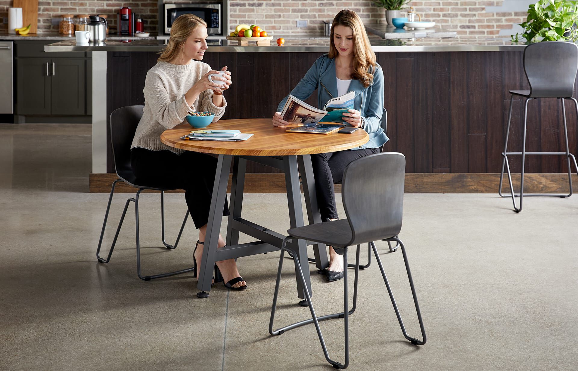 Two professionals eat a meal together sitting in the office breakroom