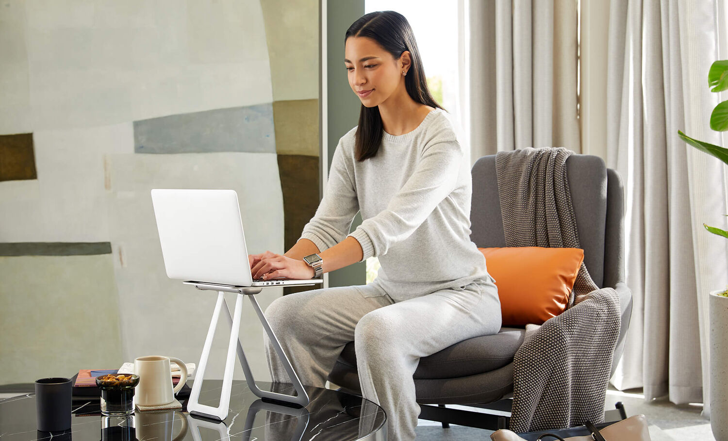 professional seated in home living room with desk mounted on portable laptop stand