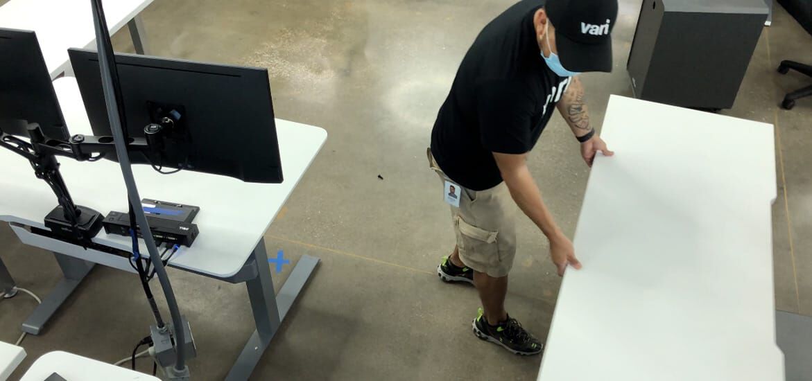 Vari employee moving table in a personal workstation to create social distance.