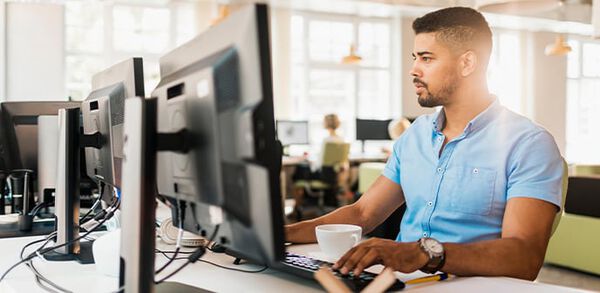 individual at desk reviewing computer monitor