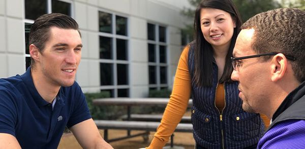 three professionals outside at a picnic table
