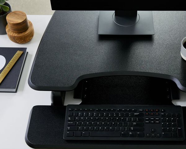 Converter raised on desk in office, keyboard tray holds mouse and keyboard
