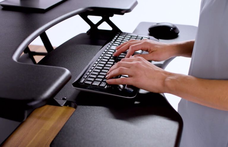 Individual typing on keyboard in standing position at desktop converter