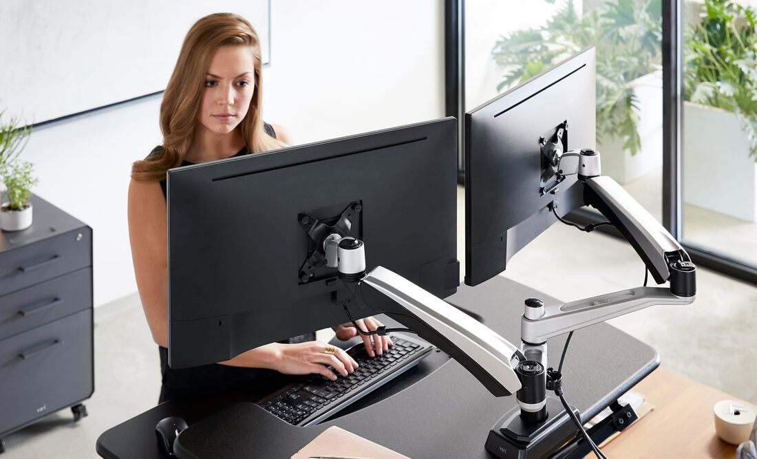 Individual looking at monitor attached to monitor arm while working at VariDesk Converter