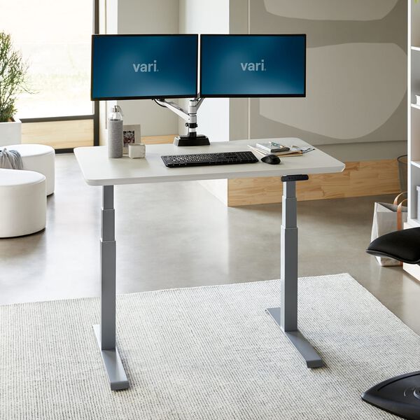 white vari electric standing desk raised in an office