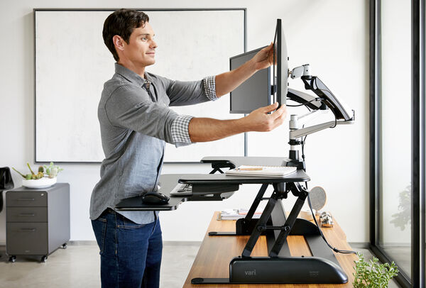 professional adjusting monitor arms on their varidesk converter