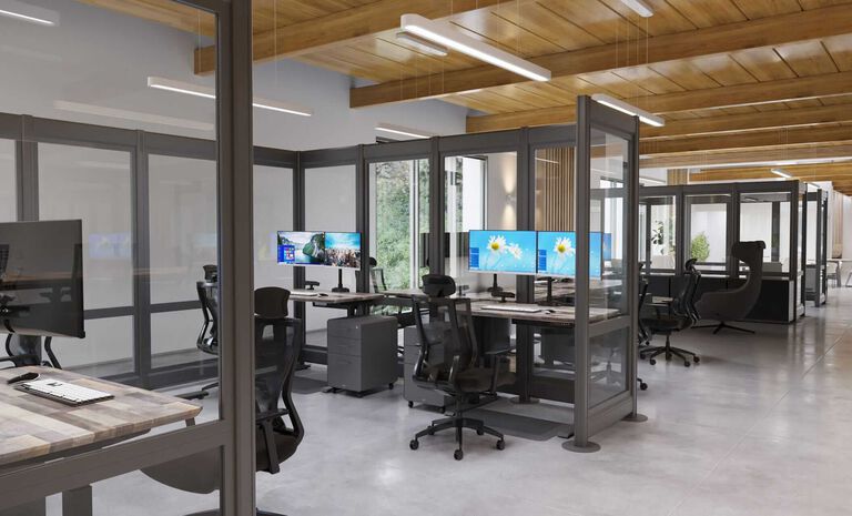 Office interior with standing desks, monitor arms, and office chairs grouped inside glass walls.
