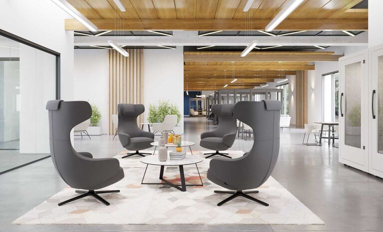 An open area with four grey lounge chairs and a coffee table where people can sit and talk.