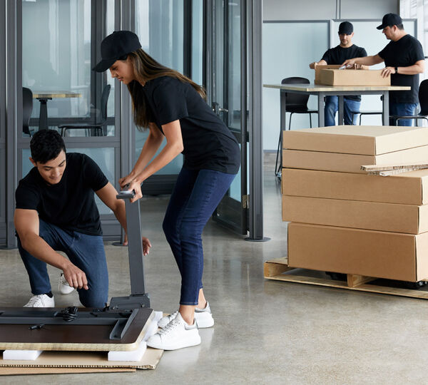 individuals working together to assemble a desk
