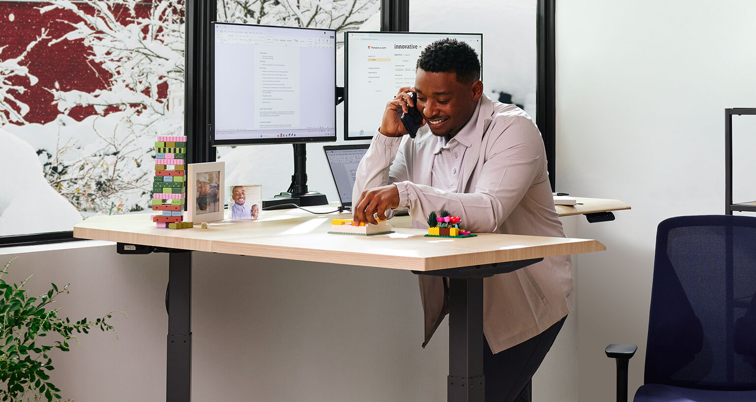 man lean on an l shape electric standing desk and talking on the phone