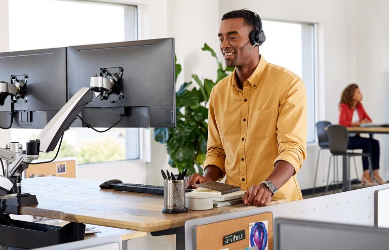 Individual working at Electric Standing Desk 60x30 with monitor arms attached