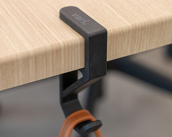 vari desk hook clamped on to a desk or table holding a bag