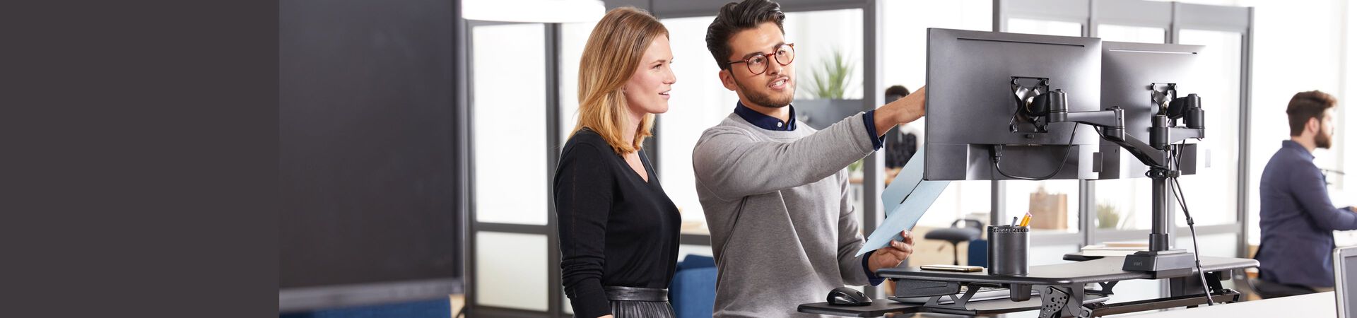 two professionals collaborate on computer work while standing at the desk