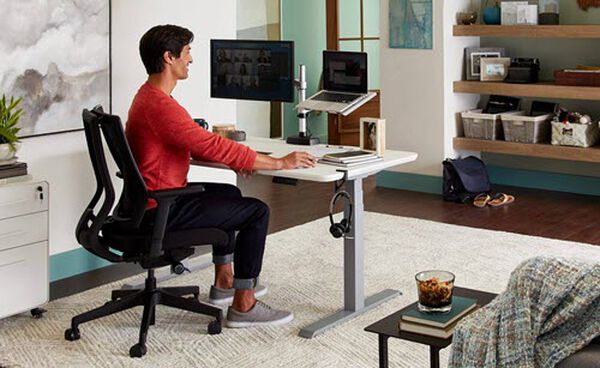 professional in home office working at electric standing desk