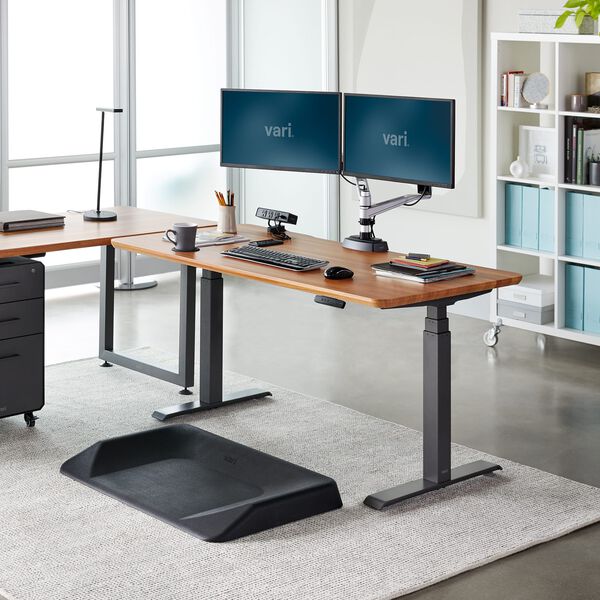 vari electric standing desk in office with monitor arms and activemat