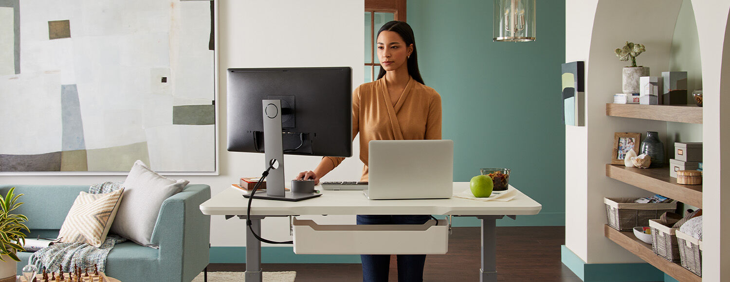 professional working in home office at electric standing desk in white