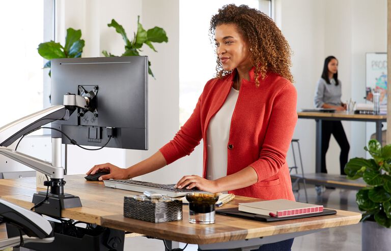 Individual working at Electric Standing Desk 48x30 with monitor arms attached