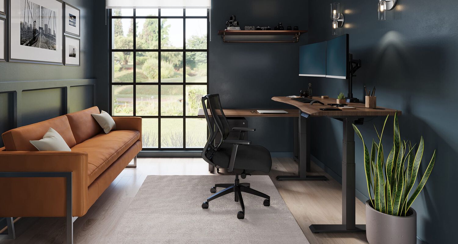 a small home office with a electric standing desk against the wall