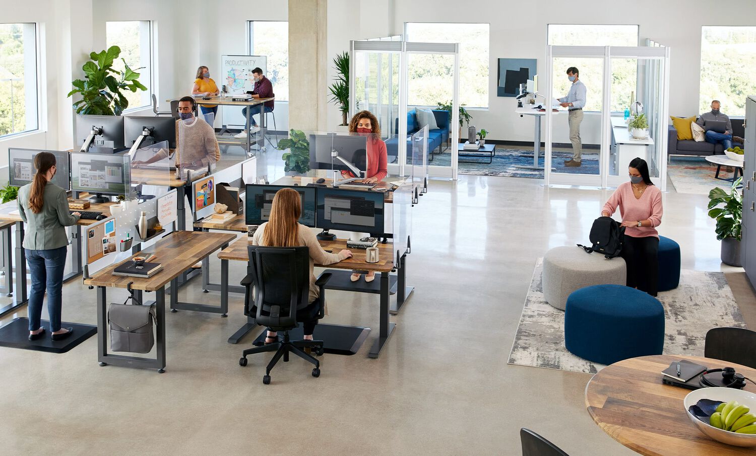 open office with several professionals at work, some in benched seating, others in private offices, and other having casual meetings, all with Vari furniture