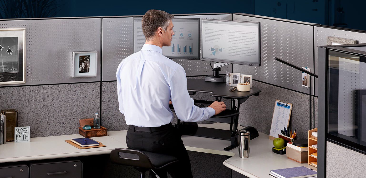 Professional working at VariDesk Converter in raised position in office