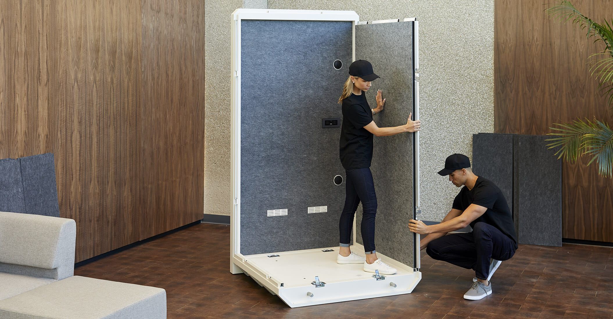 two individuals assemble the vari privacy booth in an office setting