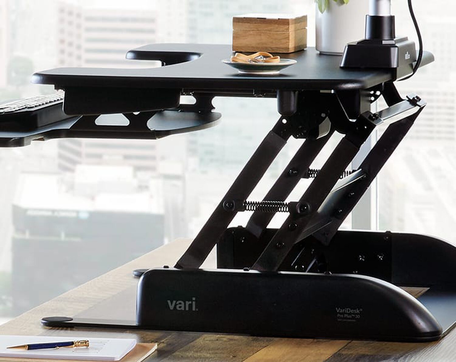 Sideview of desk converter raised halfway on exsisting desk in office setting
