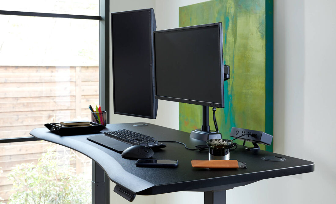 Closeup view of Curve Electric Standing Desk 60x30 desktop with mounted monitors