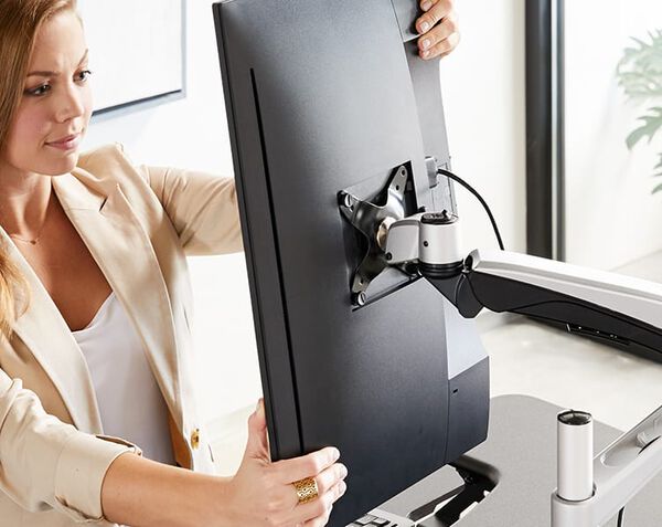 Person adjusting monitor that is mounted to monitor arm to a vertical position