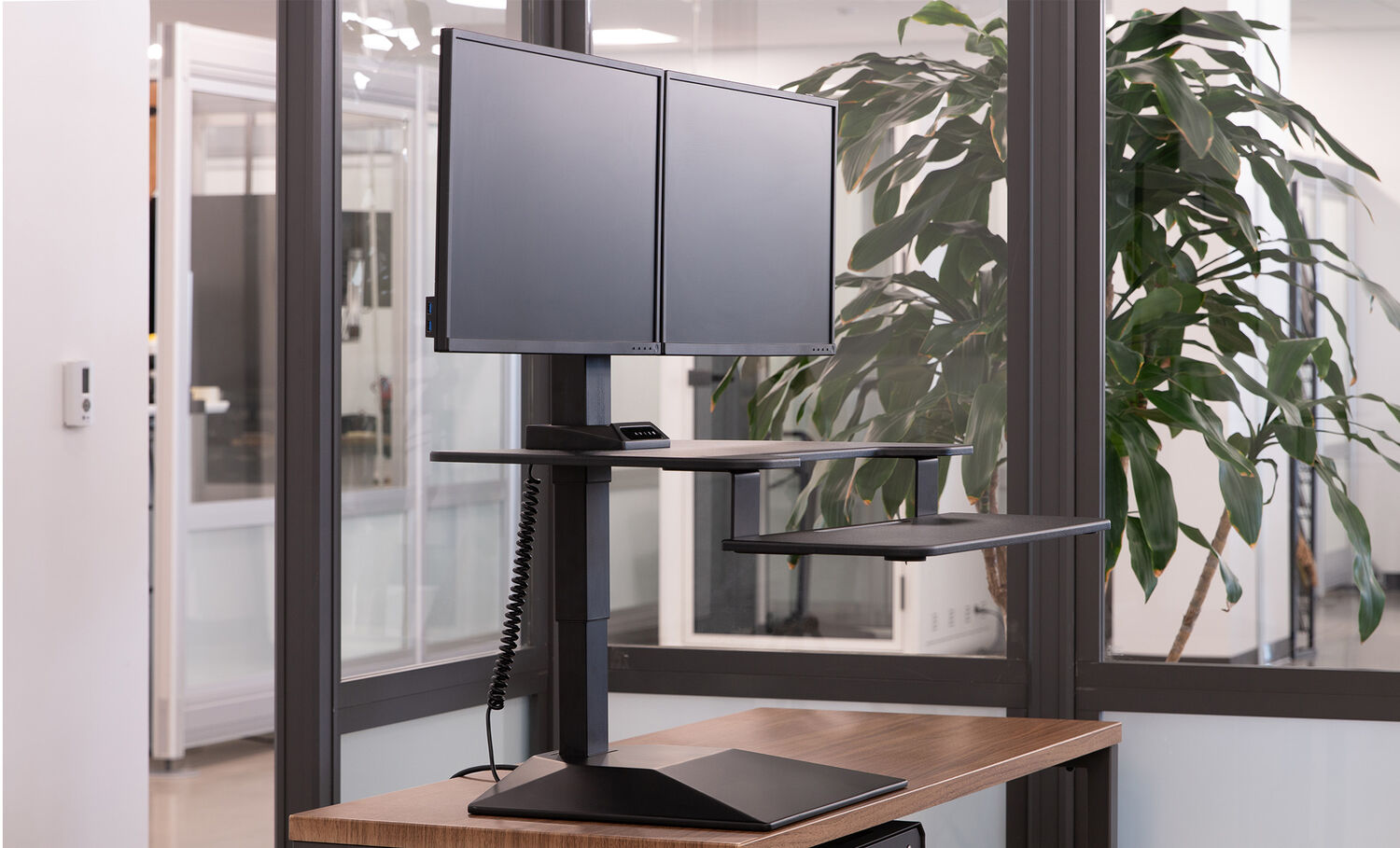 premier electric dual monitor converter in black finish in a raised position on top of a walnut table