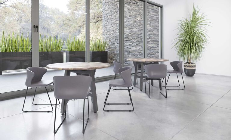 A bright café area with round top tables and comfortable seating to enjoy a meal or a casual conversation.