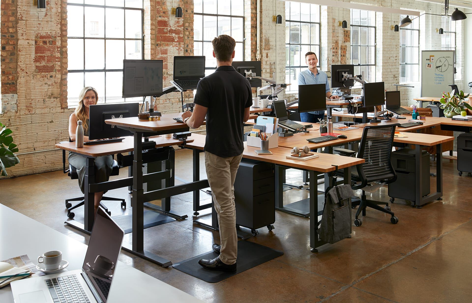 Professional creatives work in open office - they each have one traditional montior and one laptop and are able to look at both at eye-level due to the Monitor Scrren + Laptop Stand