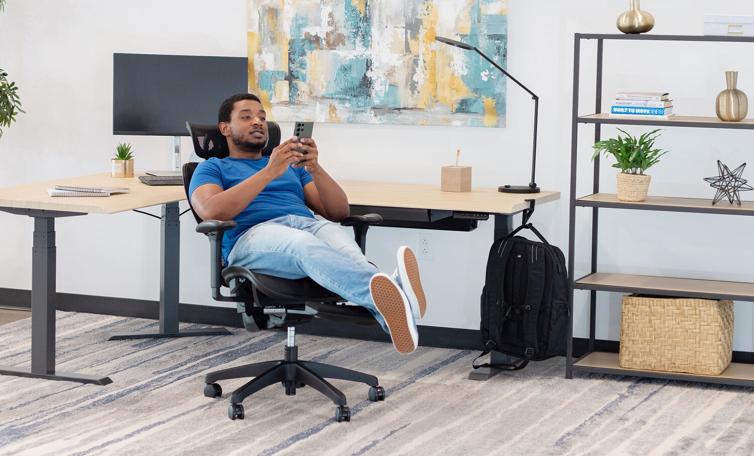 vari comfortflex office chair setup in a home office with a man leaning back with the footrest up scrolling on his phone showing