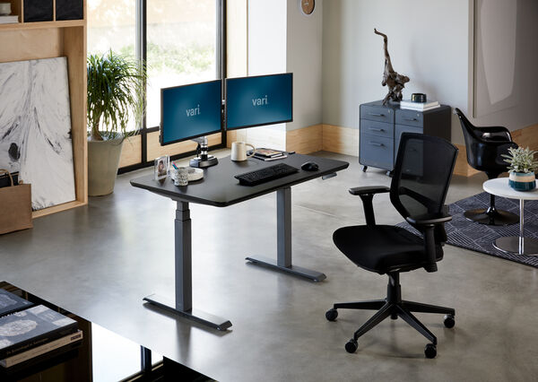 dedicated workspace comprised of vari electric standing desk, monitor arms, storage, and seating