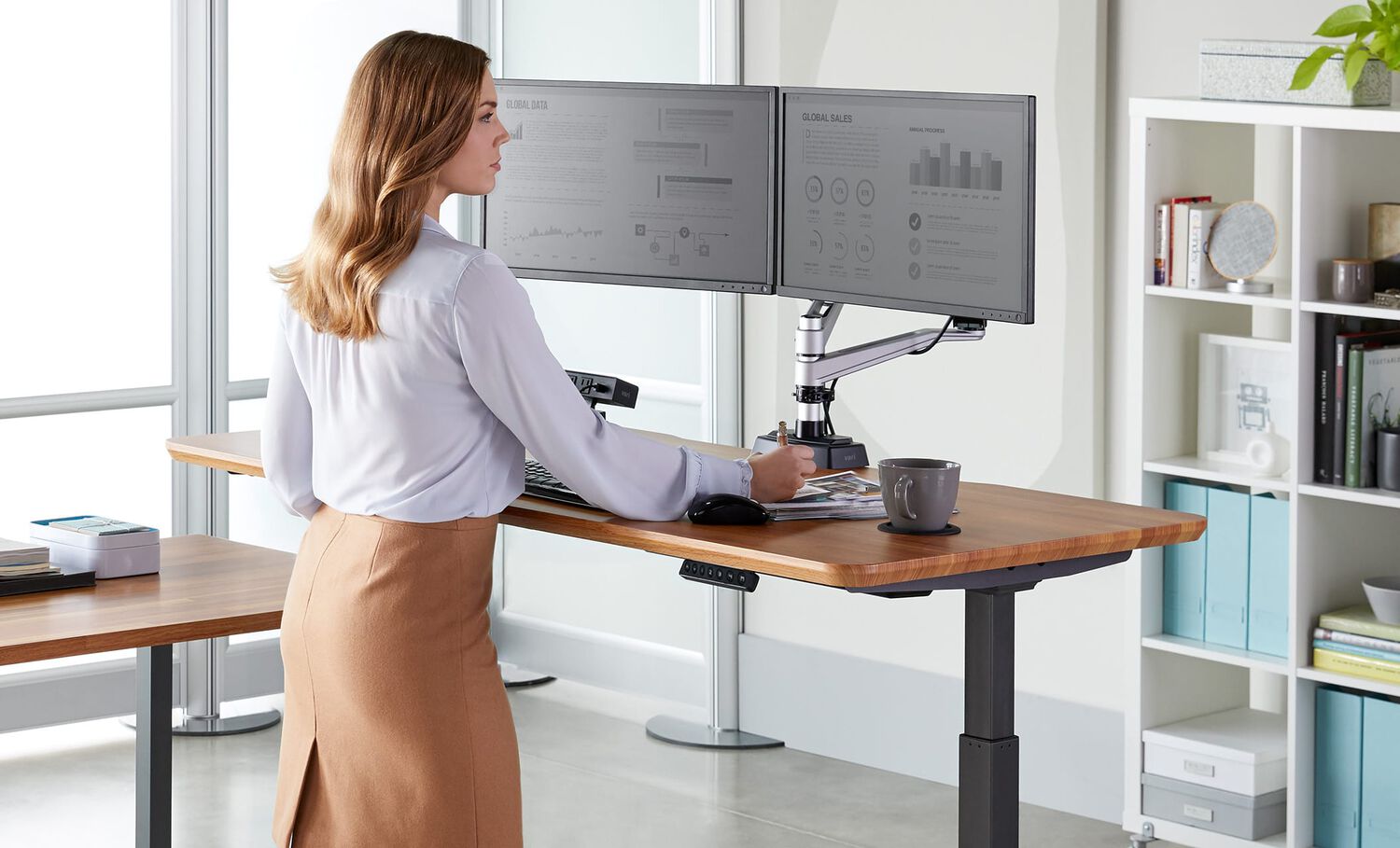 Professional standing at electric standing desk in office space