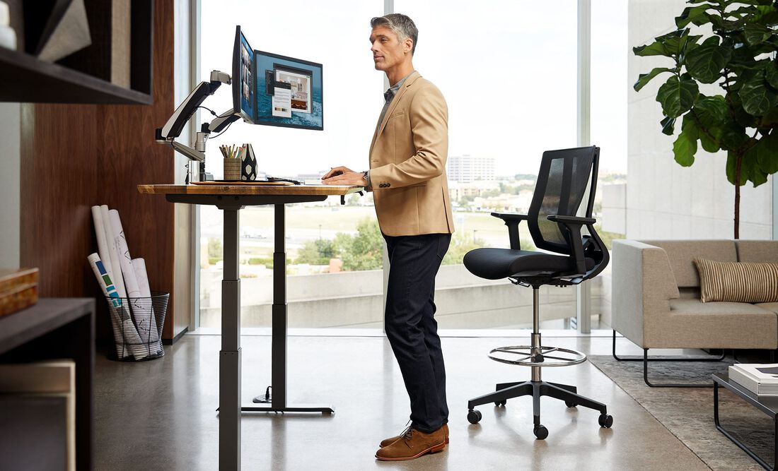 Individual standing at an electric standing desk