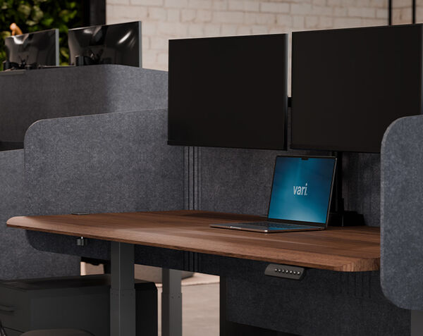 Closeup of felt privacy desk surround 72 attached to a standing desk in walnut finish