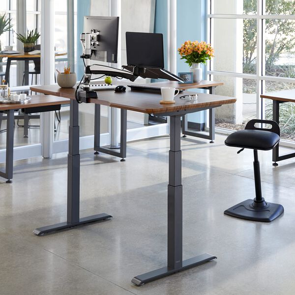 vari electric standing desk in darkwood raised in office setting