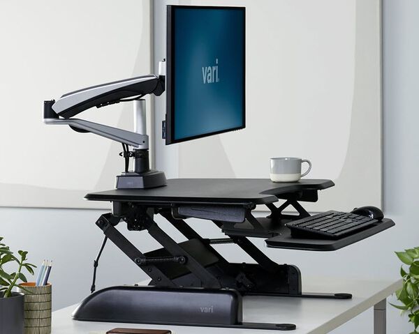 Desk riser raised to max height with a focus on the weighted base of the converter
