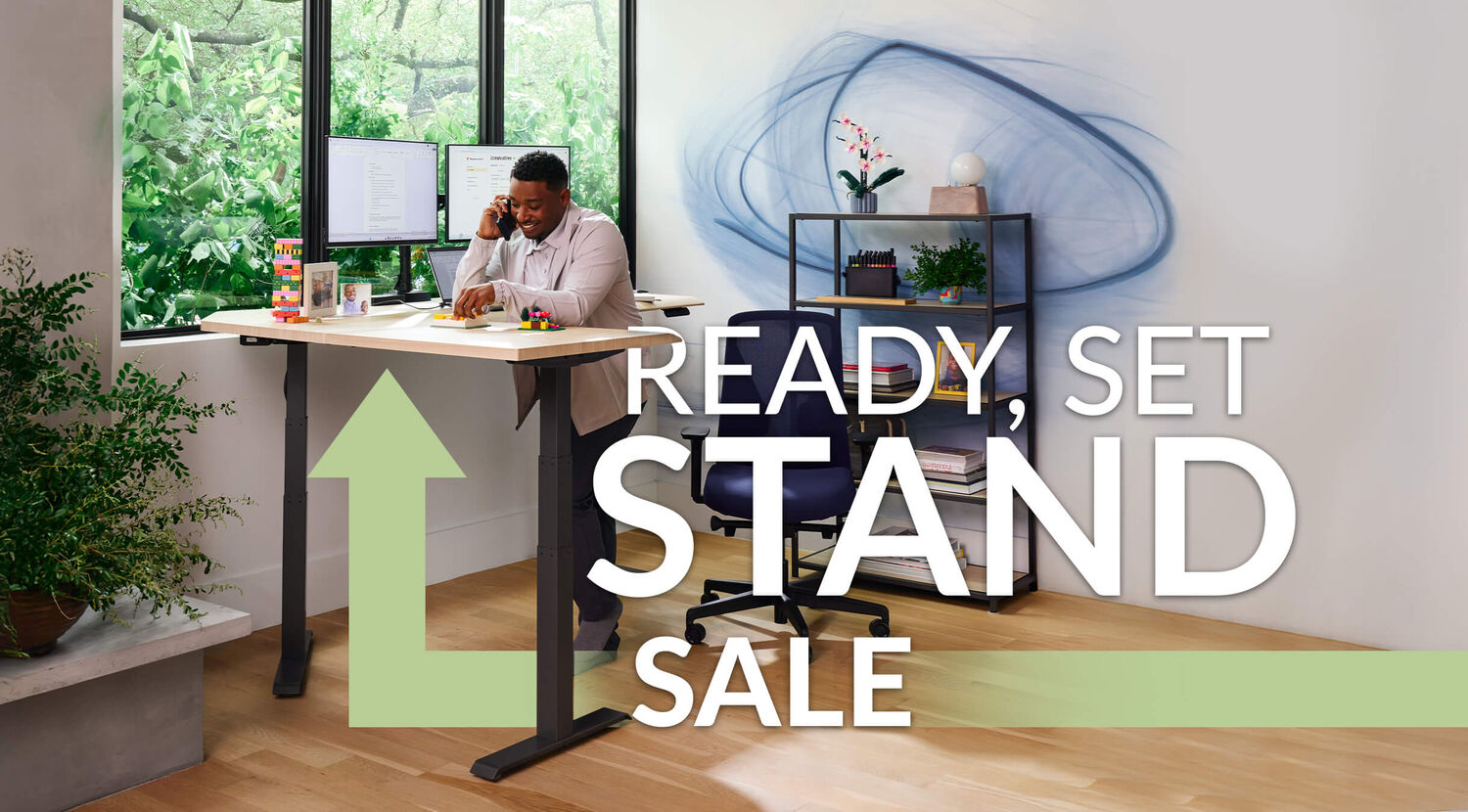 an individual standing at an l shape electric standing desk on the phone in a home office setting